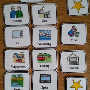 May include: A set of 15 colourful picture cards with black outlines. Each card features a different activity or item, such as sweets, friends, zoo, TV, toys, swimming, playground, outing, cinema, park, iPad, restaurant, video games, and a yellow star.