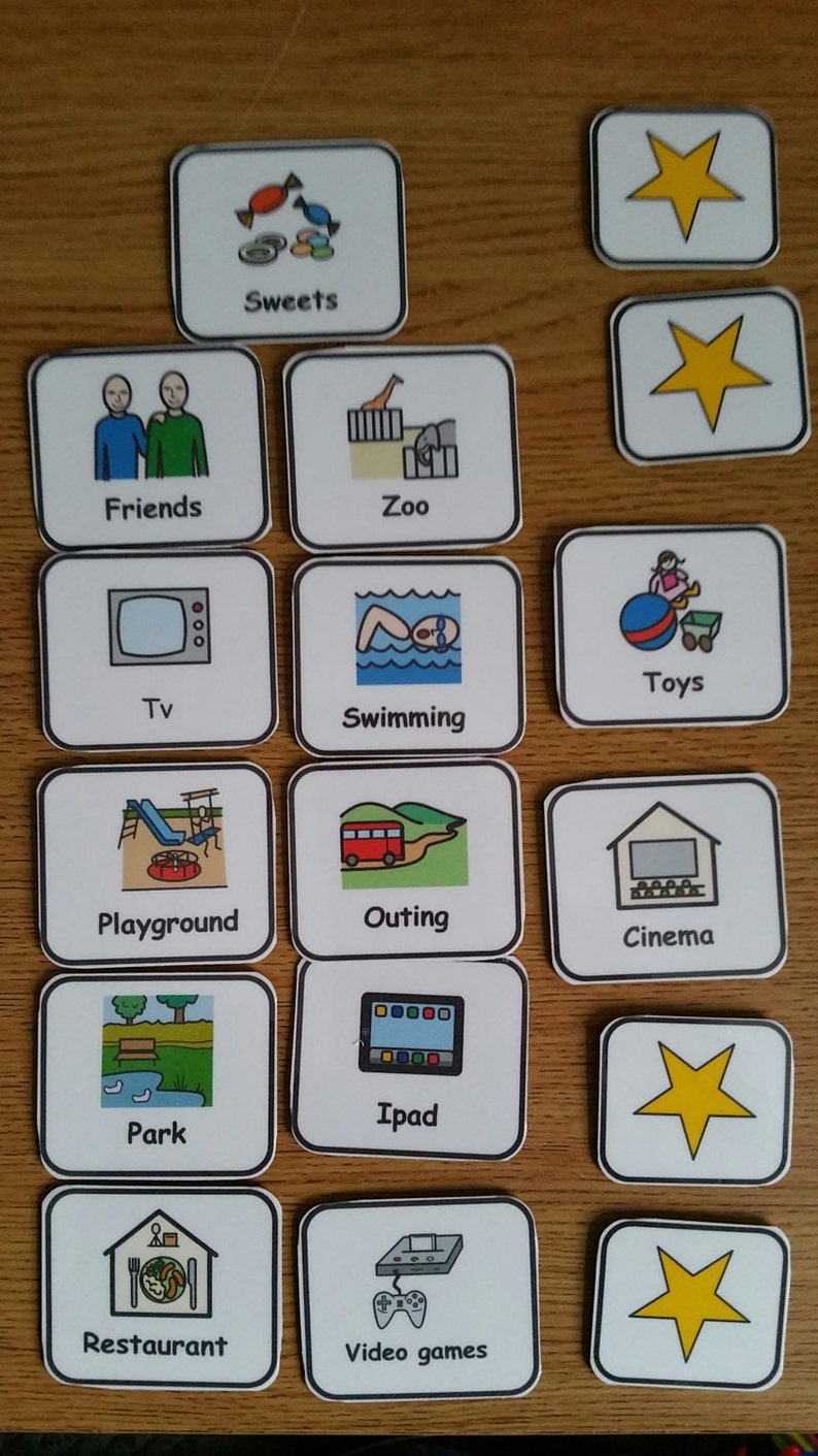 May include: A set of 15 colourful picture cards with black outlines. Each card features a different activity or item, such as sweets, friends, zoo, TV, toys, swimming, playground, outing, cinema, park, iPad, restaurant, video games, and a yellow star.