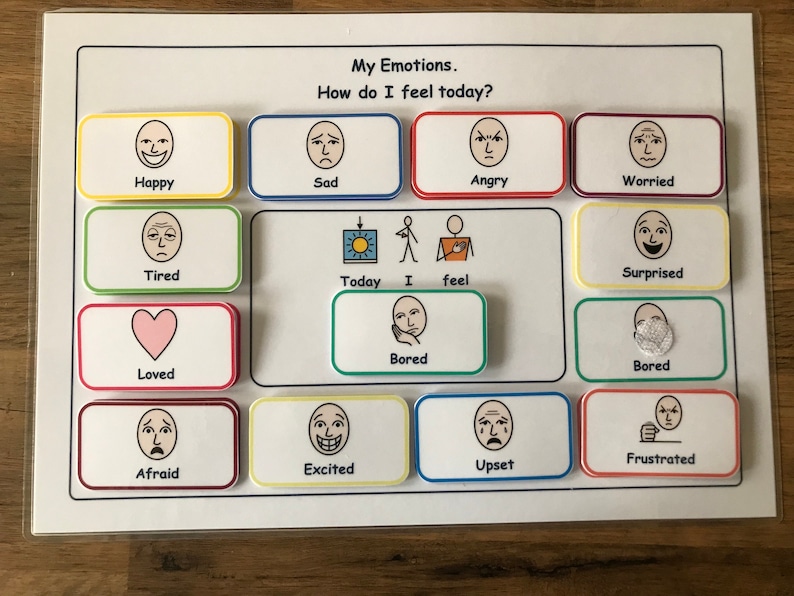 May include: A white board with colorful squares containing different facial expressions. The text "My Emotions. How do I feel today?" is at the top of the board. The squares contain images of happy, sad, angry, worried, tired, surprised, loved, bored, afraid, excited, upset, and frustrated.