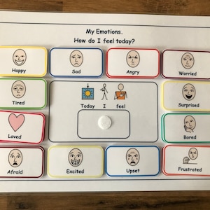 May include: A white board with colourful squares, each containing a different facial expression. The squares are labelled with words describing emotions, such as "Happy", "Sad", "Angry", "Worried", "Tired", "Loved", "Afraid", "Excited", "Upset", "Frustrated", "Surprised", and "Bored". The board also includes the words "Today", "I", and "feel".