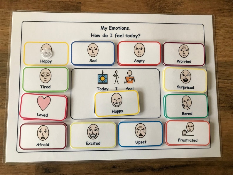 May include: A white board with colorful squares, each containing a different facial expression. The squares are labeled with words describing emotions, such as "Happy", "Sad", "Angry", "Worried", "Tired", "Loved", "Afraid", "Excited", "Upset", "Frustrated", "Surprised", and "Bored". The text "My Emotions. How do I feel today?" is at the top of the board.