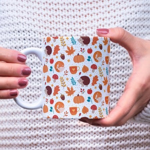 May include: White ceramic mug with a autumn-themed design featuring foxes, hedgehogs, pumpkins, acorns, and leaves in shades of orange, brown, and green.