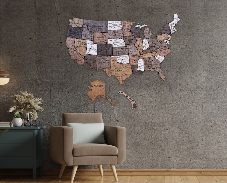May include: A wooden map of the United States with each state outlined and labelled. The map is mounted on a grey wall with a brown leather armchair in the foreground.