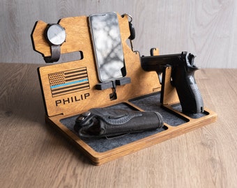 Puede incluir: Organizador de madera con una bandera estadounidense con una línea azul, el nombre "PHILIP" grabado, un soporte para reloj, un soporte para teléfono, un soporte para pistola y una funda.