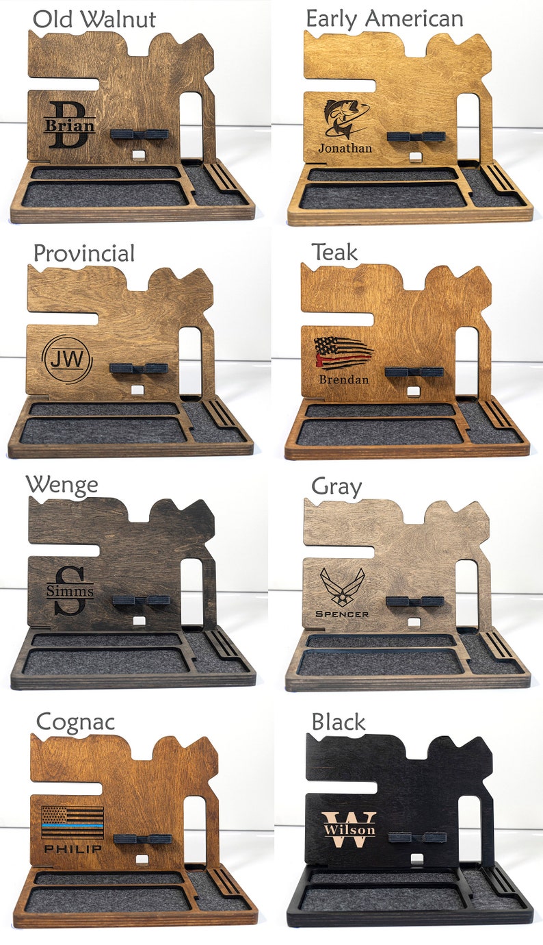 May include: Eight different wooden phone stands with various wood finishes and personalised engravings. The stands feature a phone holder, a watch holder, and a small tray. The engravings include names, initials, and symbols such as a fishing lure, an American flag, and an Air Force logo.
