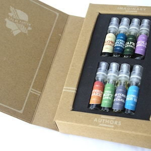 May include: A set of perfume samples in a cardboard box. The box is open, revealing small glass vials with colorful labels. The box is labeled "Imaginary Authors" and "Authors". The vials are arranged in two rows.