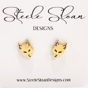 May include: Gold-toned wolf head stud earrings. The earrings are on a white card with the text "Steele Sloan Designs" and "www.SteeleSloanDesigns.com".