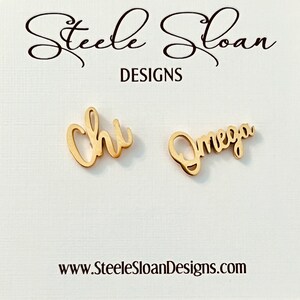 May include: Gold-colored earrings with the words "Chi" and "Omega" written in cursive.