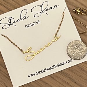May include: A gold necklace with the word "Sooner" written in cursive script. The necklace is on a white card with the text "Steele Sloan Designs" and the website address "www.SteeleSloanDesigns.com".