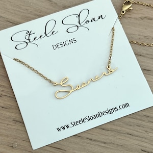 May include: Gold necklace with a cursive script pendant that says "Sooners". The necklace is on a white card with the text "Steele Sloan Designs" and "www.SteeleSloanDesigns.com".