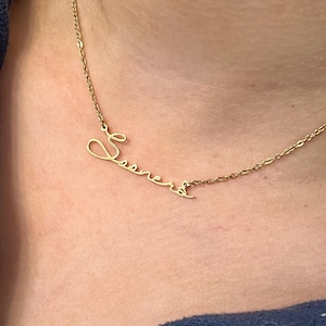 May include: A gold chain necklace with a cursive name pendant that says "Seana".