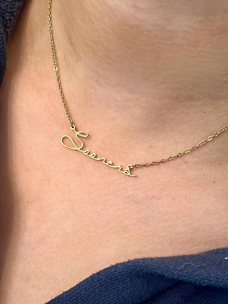 May include: A gold chain necklace with a cursive name pendant that says "Seana".