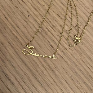 May include: A gold chain necklace with a cursive name pendant that says "Sooners".