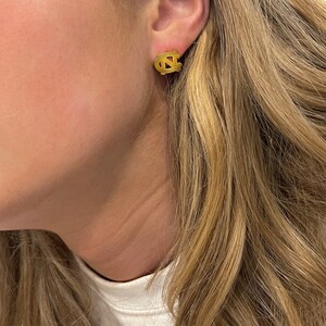 Op de afbeelding: Gouden oorbel studs met het logo van de University of North Carolina Tar Heels.