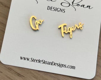 May include: Gold earrings with the words "Go Tigers" on them. The earrings are on a white card with the text "Steele Sloan Designs" and "www.SteeleSloanDesigns.com".
