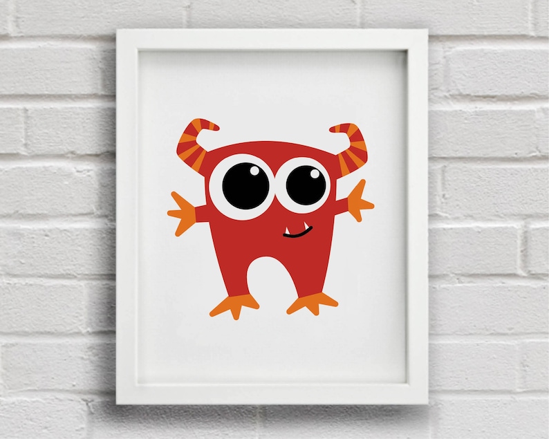 May include: A framed print featuring a cartoon monster. The monster is red with large black eyes, orange horns, and orange hands and feet. The artwork is set against a white background and framed in a white border. The image is displayed on a white brick wall.