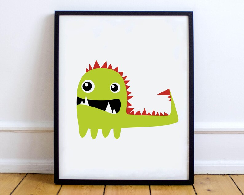 May include: A framed print featuring a cartoon monster illustration. The monster is lime green with red spikes and tail details, a wide black mouth, and large, round eyes. The artwork is set against a white background.