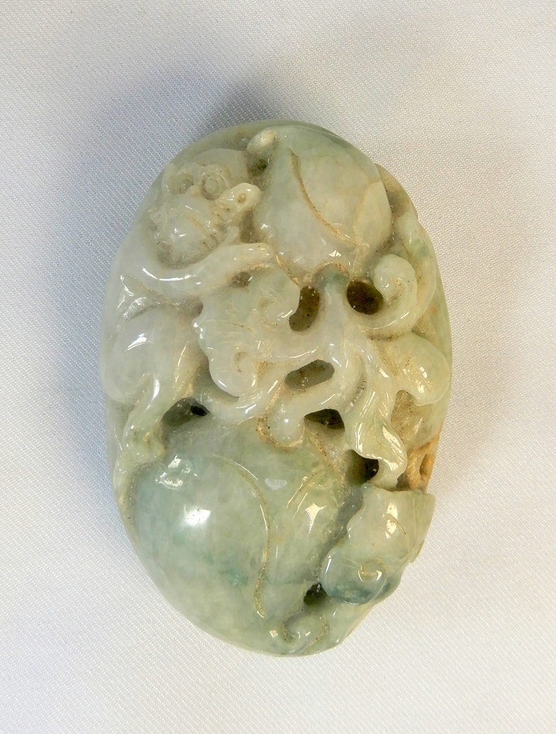 May include: A green jade carving of a dragon with intricate details. The carving is oval shaped and has a smooth, polished finish.