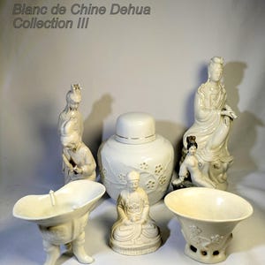 Op de afbeelding: Een verzameling witte porseleinen beeldjes en vaten. De collectie omvat beelden van figuren, een pot met deksel met bloemendetails en twee komvormige objecten. De tekst "Blanc de Chine Dehua Collection III" is zichtbaar linksboven.