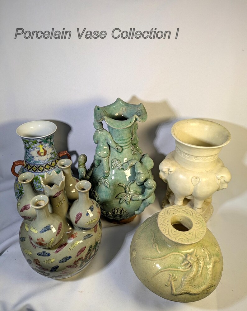 Op de afbeelding: Een verzameling porseleinen vazen in diverse vormen en kleuren. De vazen omvatten een groene vaas met figuren, een cr&egrave;mekleurige vaas met een brede opening en een vaas met een cluster van kleinere vazen. De tekst "Porcelain Vase Collection I" is zichtbaar.