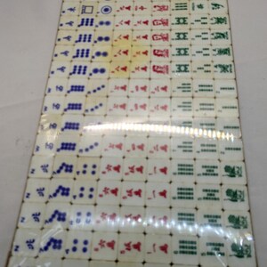 May include: A complete set of vintage Mahjong tiles, arranged in a rectangular pattern. The tiles are off-white with symbols in red, green, and blue. The set is packaged in clear plastic, suggesting it is a complete game set.
