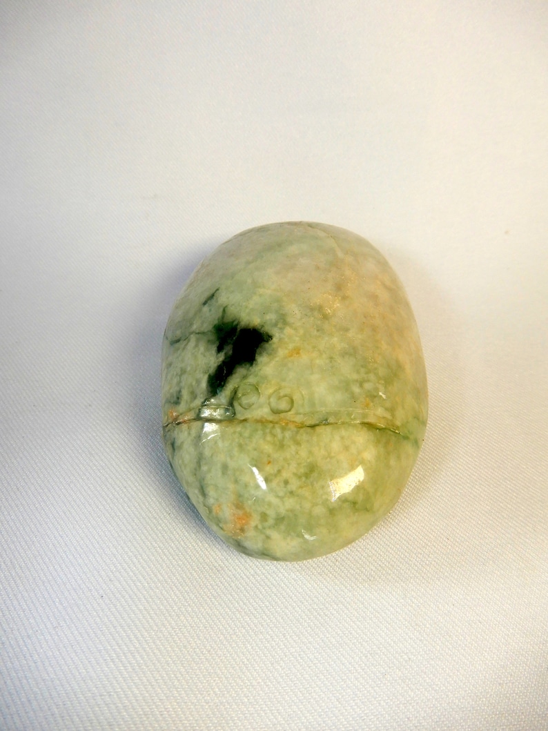 May include: A smooth, oval-shaped green and white stone with a darker green patch. The stone has a glossy finish.