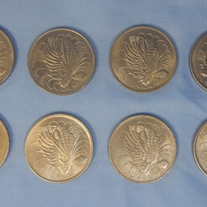 May include: Eight silver-coloured coins with a design of a bird with a fan-shaped tail on each side.