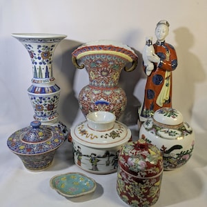 Op de afbeelding: Een verzameling Famille Rose porseleinen items, waaronder vazen, potten met deksel en een beeldje. De stukken hebben ingewikkelde bloemen- en figuurontwerpen in rood, blauw en goud. De tekst "Famille Rose Collection I" staat bovenaan.