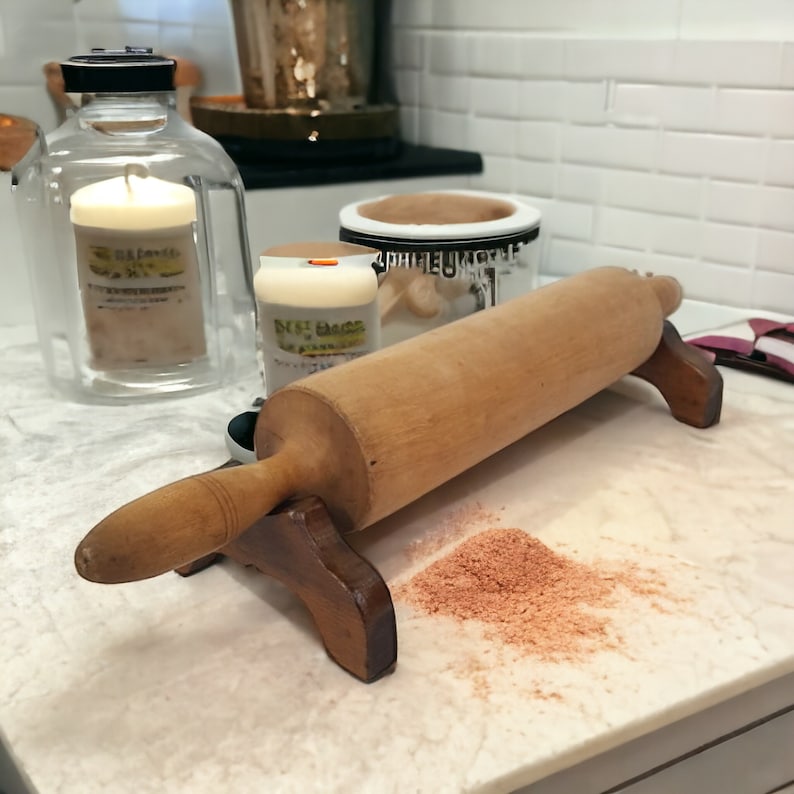 May include: A wooden rolling pin with a brown wooden stand on a white countertop. There is a small pile of brown powder on the counter.
