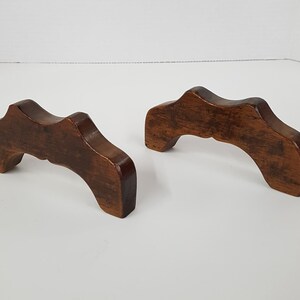 May include: Two wooden bookends with a curved top and a dark brown finish.