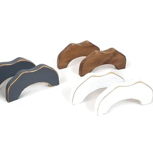 May include: Set of six wooden arches in three colors: gray, brown, and white. The arches are painted and have a gold accent around the top edge.