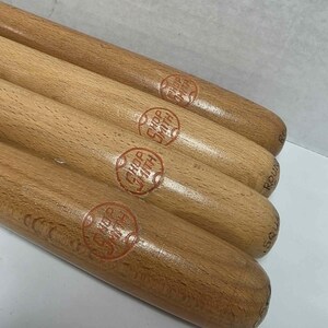 May include: Four cylindrical wooden turning chisels or tool handles arranged in a parallel row. Each light brown wooden handle features a circular red brand stamp that reads Shopsmith. The ends of the handles show partial text labels.