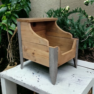 May include: A wooden pet bed with a raised edge and a metal frame. The bed is painted a light brown color and has a natural wood finish. The metal frame is painted a silver color and has a distressed look.