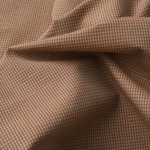 May include: A piece of fabric featuring a small-scale gingham pattern in shades of muted terracotta orange and off-white. The textile is draped to show folds and creases, highlighting the consistent grid design across the woven surface of the cloth.