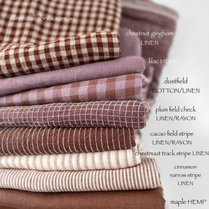 Op de afbeelding: Een stapel verschillende stofstalen in bruin- en paars tinten. De stoffen omvatten ruitjes, strepen en effen kleuren. De tekst op de afbeelding luidt "allnaturalfabrics.com.au" en vermeldt stofsoorten zoals linnen en hennep.