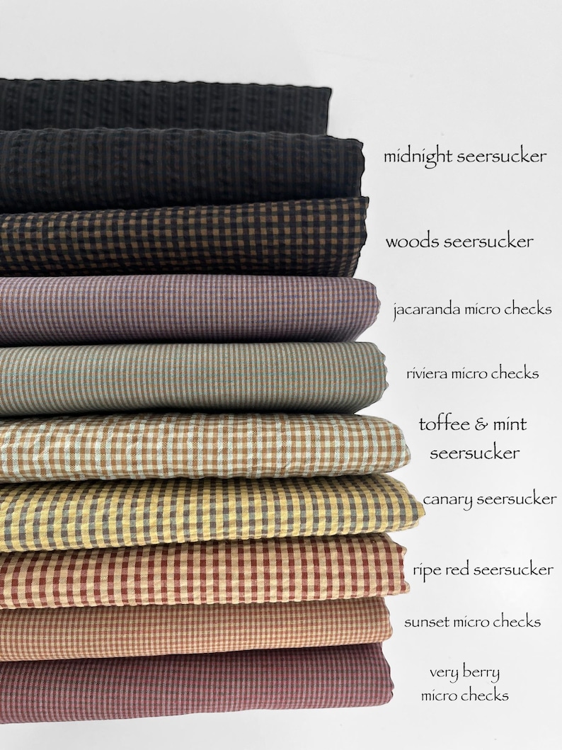 May include: A stack of nine folded fabric swatches featuring various checkered and seersucker patterns. The labels include midnight seersucker, woods seersucker, jacaranda micro checks, riviera micro checks, toffee & mint seersucker, canary seersucker, ripe red seersucker, sunset micro checks, and very berry micro checks.