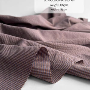 May include: Jacaranda micro checks fabric featuring a blend of 60% cotton and 40% linen. The material has a weight of 115gsm and a width of 138cm. The textile displays a fine, repeating checkered pattern in muted mauve and brown tones.