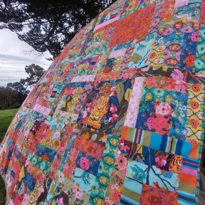 Peut inclure: Une courtepointe patchwork colorée avec une variété d'imprimés floraux et animaliers. La courtepointe présente un grand imprimé de tigre au centre, entouré de carrés plus petits de différents motifs. La courtepointe est faite de divers tissus, dont le coton et la soie.