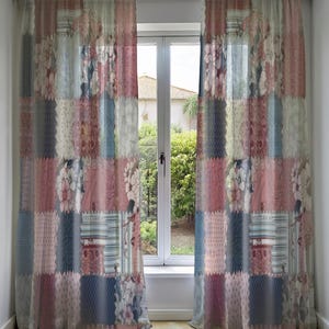 Puede incluir: Dos cortinas transparentes de patchwork con un estampado floral y geométrico. Las cortinas presentan cuadrados de telas rosas, azules y blancas. Las cortinas cuelgan frente a una ventana.