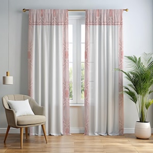 May include: A pair of floor-length curtains featuring a white center panel and a dusty rose border with a geometric star-like pattern. The curtains are hung on a gold-toned rod and frame a window, displaying a semi-sheer fabric texture.
