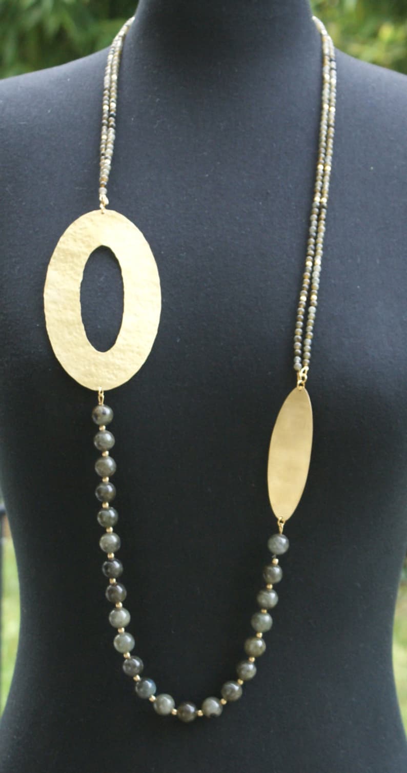 May include: A gold necklace with two oval-shaped pendants and a strand of dark grey beads.