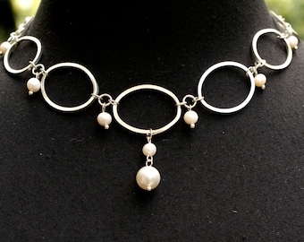 May include: A silver necklace with a series of oval and round links, accented with white pearls. The necklace has a single pearl drop pendant.