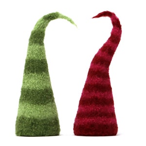May include: Two felt elf hats, one green and one red, with white stripes. The hats are standing upright on a white background.