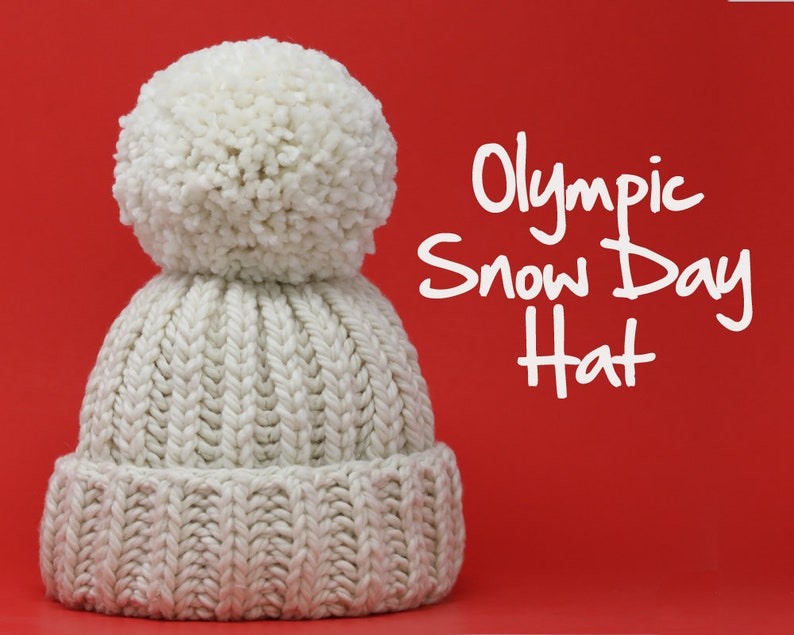 May include: A white knitted hat with a large white pom-pom on top. The hat is on a red background and the text "Olympic Snow Day Hat" is written in white letters.