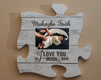 May include: A white puzzle-shaped photo frame with a distressed wood grain finish. The frame holds a photo of a baby and has the text "Makayla Faith" and "I LOVE YOU to the MOON & BACK" in black script.