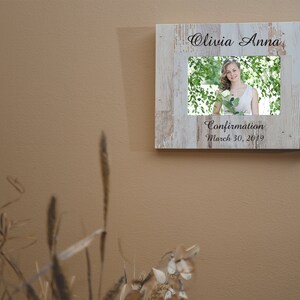 May include: A white wooden picture frame with a photo of a young woman in a white dress. The frame has the text "Olivia Anna" and "Confirmation March 30, 2019" engraved on it.
