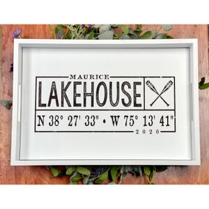 May include: White wooden serving tray with a black and white graphic design. The design features the text "MAURICE LAKEHOUSE" with crossed baseball bats and coordinates "N 38° 27' 33" W 75° 13' 41" 2020".
