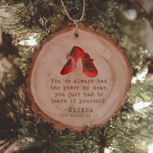 May include: A wooden Christmas ornament with a red ruby slipper design and a quote from Glinda the Good Witch from the Wizard of Oz: "You've always had the power my dear, you just had to learn it yourself." - Glinda The Wizard of Oz