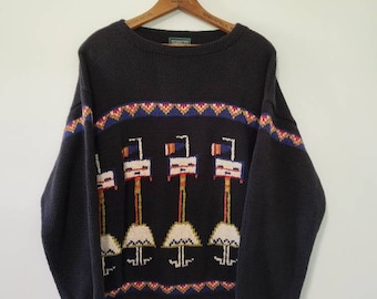 May include: A black knitted sweater with a colorful pattern of birds and a geometric design. The sweater has a crew neck and long sleeves.