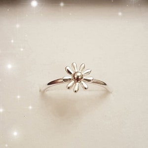 Puede incluir: Un anillo de plata con un delicado diseño de margarita. El anillo es simple y elegante, perfecto para el uso diario.